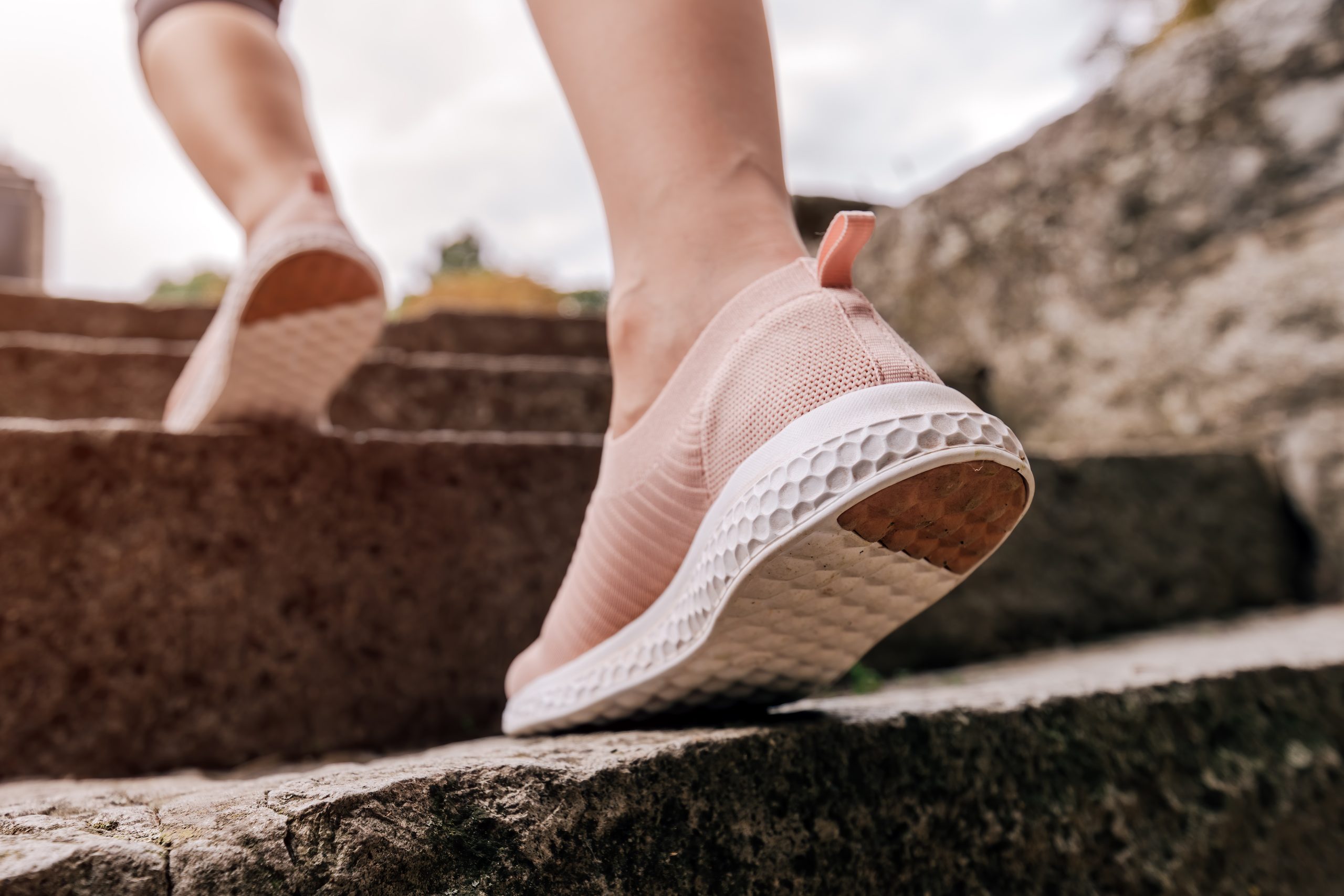 A close up of a woman ascending a set of stone stairs wearing nice shoes. Injury Rehab is here to help you get back on your feet.